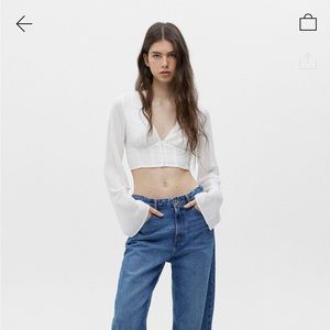 New White cropped top with a V-neck and flared sleeves.